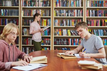 To gutter og en jente på bibliotek og studerer