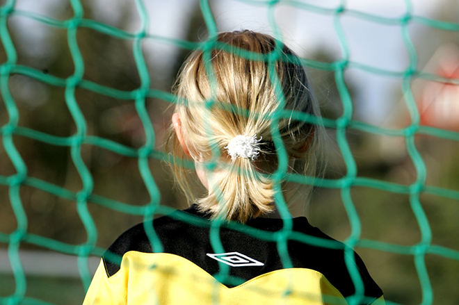 Bildet viser en ung jente som står i mål på en fotballbane. 