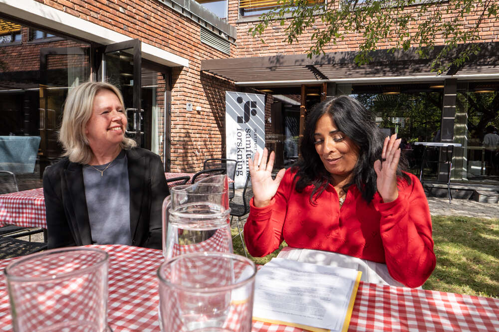 Forsker og ny senterleder Kari Steen-Johnsen (til venstre) med kultur- og likestillingsminister Lubna Jaffery (til venstre) ved bord i forhagen til ISF. Foto: Knut Strand